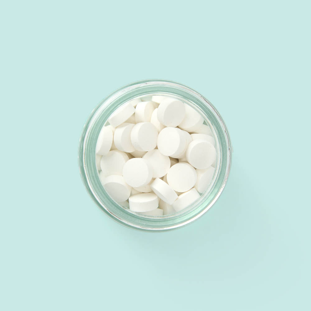 Eco-friendly toothpaste tablets in a zero-waste jar with whitening and plaque-removing ingredients